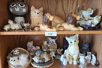 Shelved collection of assorted cat decor including plush and figurines arranged with a white note labeled '038'
