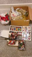 Wide view of all items packed in boxes including tinsel and ribbons, assorted small ornaments, and boxed glass ornaments