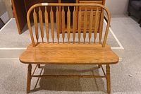 Front view of the wooden bench showing curved seat and spindle-back design