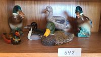 Front view of all six duck and loon figurines displayed on wood shelf