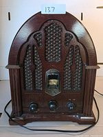 Front view of the General Electric antique style radio showing arch top wooden cabinet, grille cloth, and control knobs.