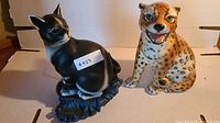 Front view of black cat statue and painted jaguar statue side by side