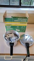 New Presto pressure cooker with box, lid, and instruction manuals.