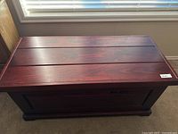 Front view of reddish wooden chest showing panel design and smooth finish.