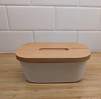 Butter or pate dish closed showing white ceramic base and wooden lid with central oval cutout.