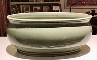 Side view of the oval ceramic celadon bowl showing smooth crackle glaze and reflective surface.