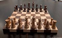 Chess set arranged on board showing full set of wooden chess pieces in natural light and dark finishes