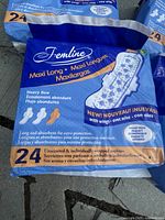 Close-up of a single unopened package of FemLine Maxi Long sanitary pads showing product details, package color, and quantity (24 pads)