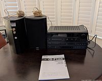 Full stereo system set including Sony amplifier, TEAC CD player, pair of Insignia speakers with cords, and TEAC CD player manual on table.