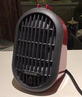 Front view of the bright red Honeywell mini-ceramic heater with black grille and brand logo visible.