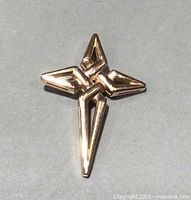 Front view of pendant on gray background showing geometric openwork cross design.