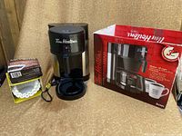 Photo showing Tim Hortons coffee maker next to original box and coffee filters on table.