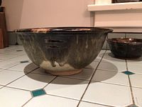 Large green and cream handmade pottery bowl side profile showing glaze and base.