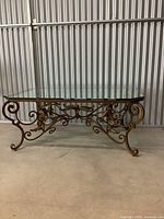 Full frontal view of entire coffee table showing glass top and iron scroll base