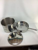 Faberware large pot with lid shown separately with the frying pan next to it on white surface.