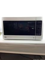 Front view of LG white countertop microwave oven with a tinted black door and LG logo.