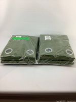 Two sets of green blackout curtains in packaging, stacked side by side