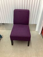 Front view of the purple accent chair showing its straight back and cushioned seat with wooden legs.