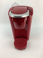 Front angled view of red Keurig coffee maker showing water reservoir, drip tray, and coffee pod compartment.