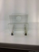Front angled view of the vintage acrylic magazine holder showing clear acrylic panels and metal supports.
