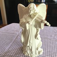 Front view of the ceramic angel figurine, white matte finish, detailed wings, holding violin and bow.