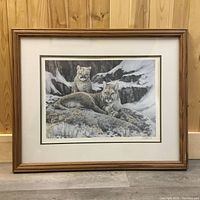 Frontal image showing the framed art print of two mountain lions in their natural rocky habitat. Clear view of the print, wooden frame, and matting.
