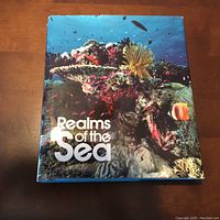 Photo of the book titled 'Realms of the Sea' by National Geographic with a colorful underwater coral reef cover.