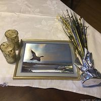 Photo showing all items in the lot: framed mallard duck painting, two gold decorative candles, and dried flower arrangement with gold and silver tones.