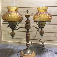 Vintage Vilas dual globe lamp with amber honeycomb glass globes, wooden stand, and electrical cord. One globe shows broken piece.