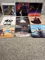 All nine album covers arranged in three-by-three grid on carpeted floor