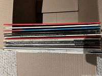Stack of about 12 comedy vinyl LPs in open box, spines visible