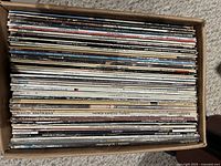 Box filled with tightly packed LP records viewed from top, spines visible