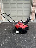 Side view of Toro CCR 2450 red and black snowblower showing handle, wheels and chute