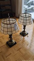 Pair of vintage brass table lamps displayed on parquet floor near window