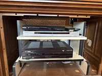 Wide shot showing Sony DVP-SR400P and DVP-NSS575P DVD players stacked on a shelf above the Cisco NextBox Explorer 8642HD cable box.