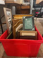 Red bin holding various sizes and styles of picture frames from 5x7 to 18x16 inches.