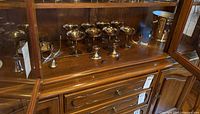 Shelved display with 10 silver plate champagne coupe glasses and silver plate ice bucket.