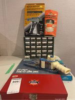 Photo showing full lot contents: tap and die set box, plastic drawer organizer, two boxed fastener kits, tape dispenser.