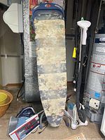 Photo showing the ironing board, T-Fal steam iron on the floor, part of the Tobi clothes steamer stand to the right, broom and mop.