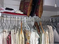 Photo showing multiple tablecloths and runners hung on a rack with various fabrics and patterns including lace