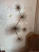 Frontal view of five starburst metal wall art hung on floral wallpaper