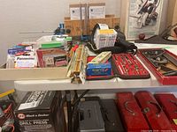 Overview of the table showing assorted tools, batteries, picture hanging kits, and tool cases