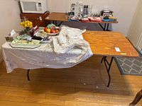 Wood top utility table with folding metal legs set up inside a room with some items on it, not included in the sale.