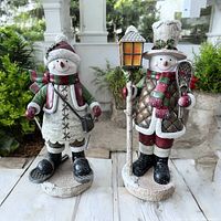 Two handcrafted 14-inch poly resin snowman figurines displayed outdoors, showing full front view of both items to illustrate design, size and condition.