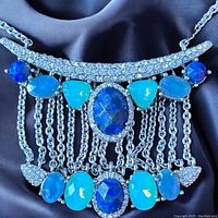 Front close-up showing the detailed design of the silver necklace with blue and turquoise faceted glass stones.