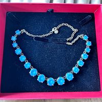 Full view of blue stone necklace in black and red box with velvet holder