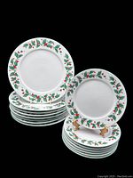 Stack of Christmas dinner and dessert plates, showing holly leaf and berry pattern around rims. Two sets stacked separately with plates of different sizes.