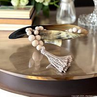 Decorative horn dish displayed on brass coffee table with a neutral wooden bead garland with tassel.