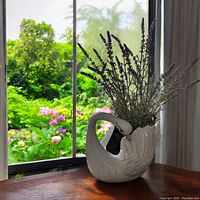 Porcelain swan planter displayed near a window with plants inside.