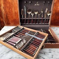 Open teak case showing two trays of flatware and lid insert.